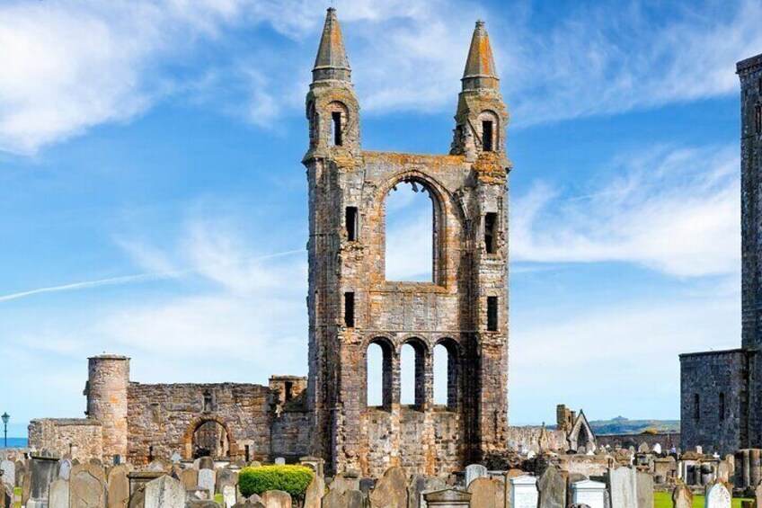 A historic stone structure with arches and towers, surrounded by other ruins and tombstones. 2