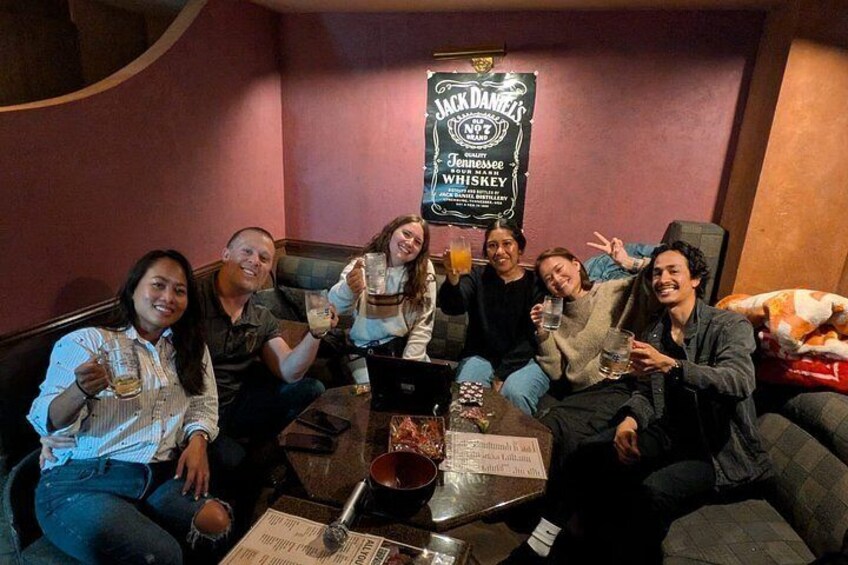 Un groupe de personnes est assis autour d’une table, devant des boissons, un panneau publicitaire pour le whisky Jack Daniel’s du Tennessee et un ordinateur portable. 3