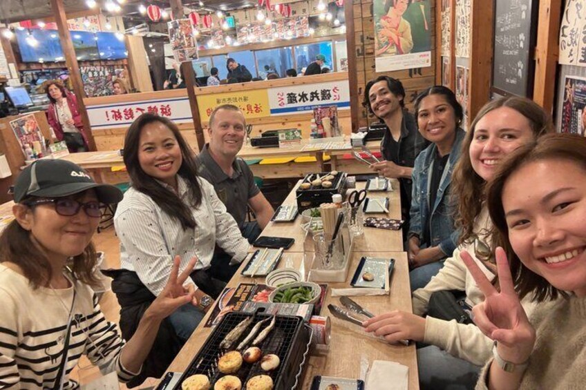 Un grupo de personas en un restaurante con una parrilla y varios platos en la mesa. 5