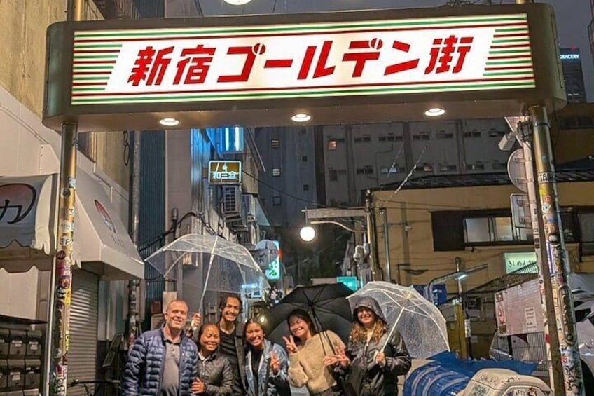 En grupp människor som poserar under en skylt med japanska tecken. 2