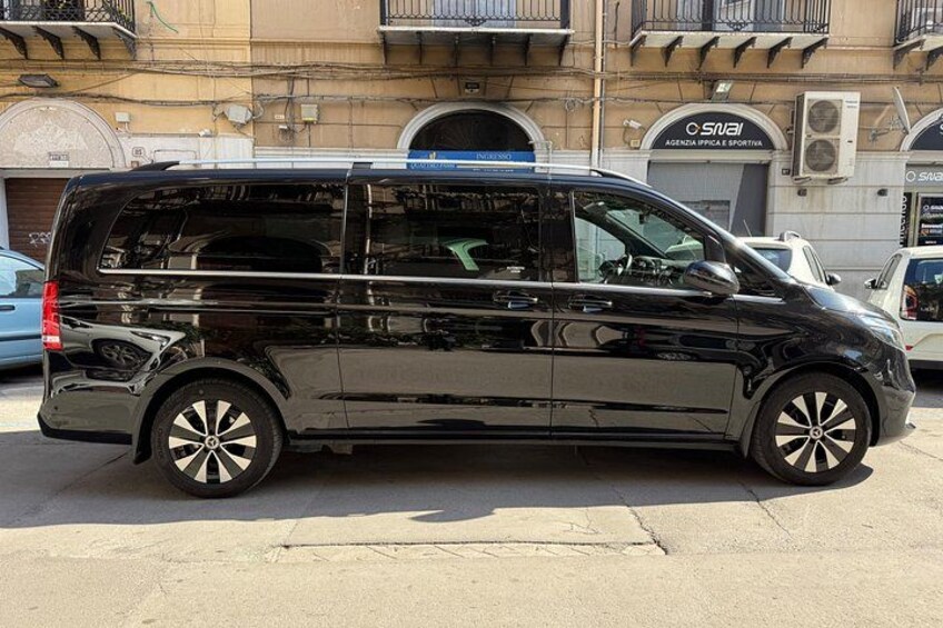 Una camioneta negra estacionada en una calle con edificios al fondo. 2