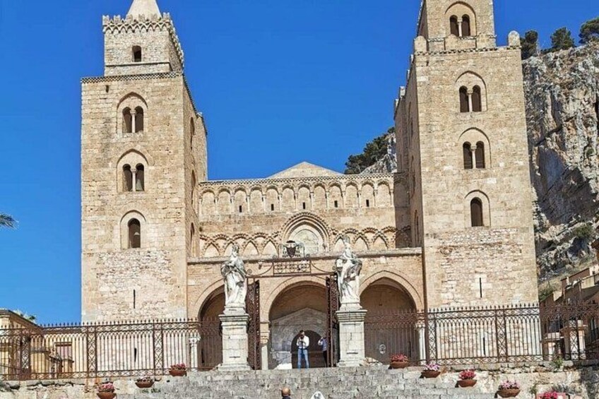 Un edificio histórico con dos torres, entradas en arco y estatuas. 3