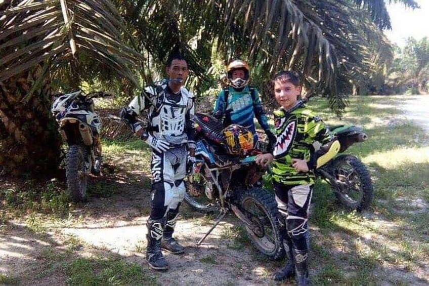 Three individuals in motocross gear standing next to a dirt bike. 3