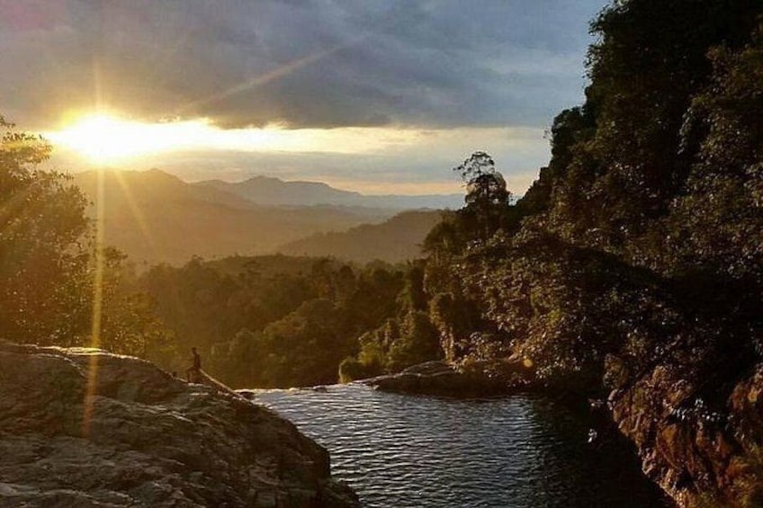 A river flowing through a mountainous landscape with the sun setting in the background. 2