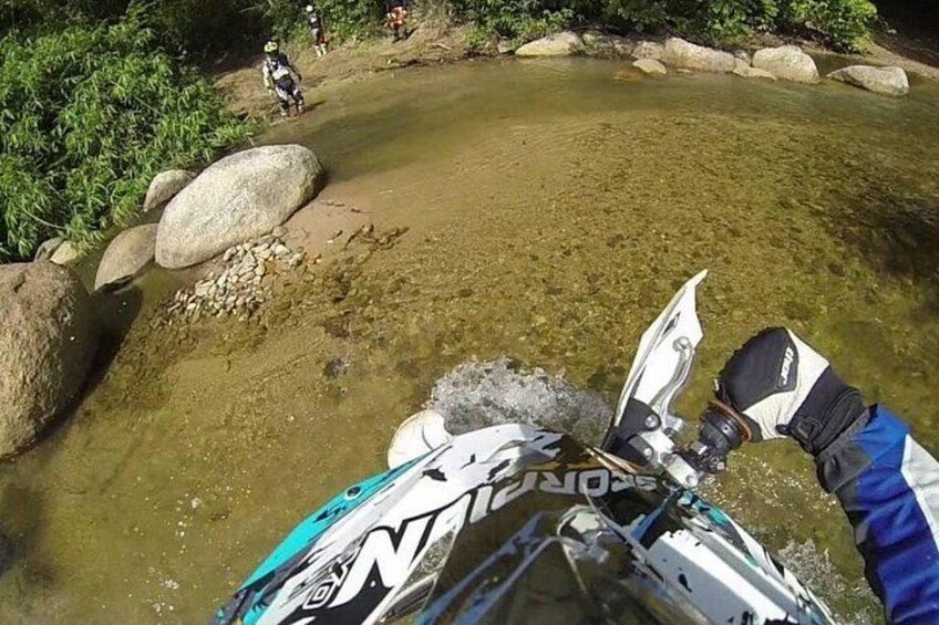 A person on a white and blue watercraft navigating a shallow, rocky river. 2