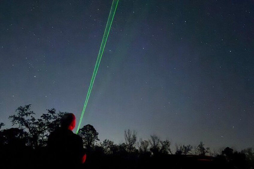 A person observing the night sky with a green laser beam. 5