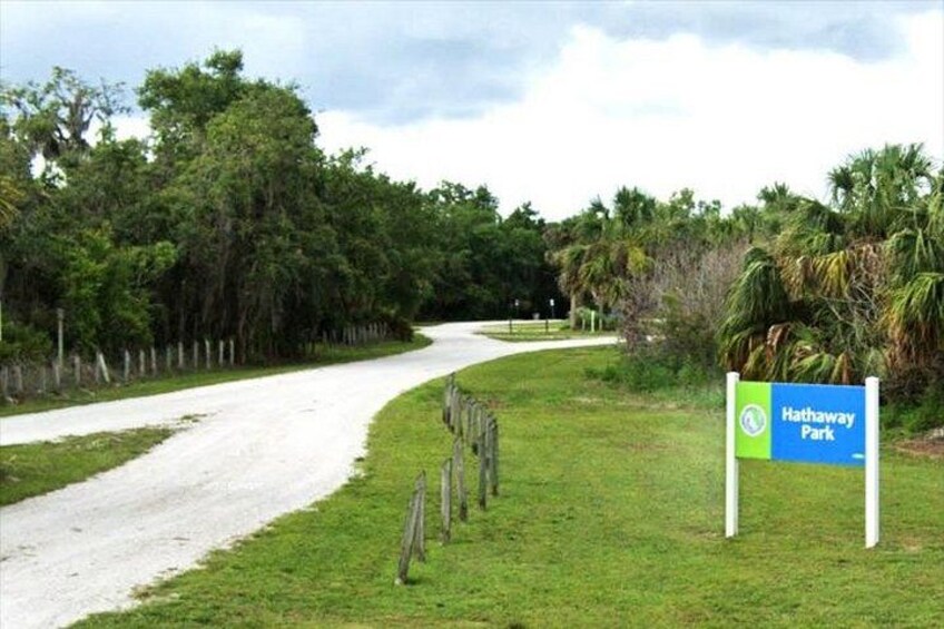 A dirt road curving through a grassy area with a sign for Hathaway Park. 2