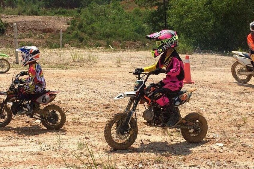 Two people riding dirt bikes on a dirt track. 4