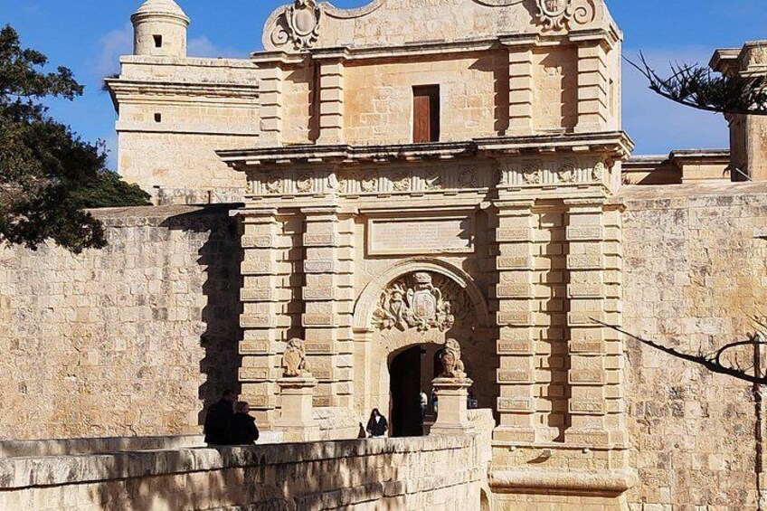 A historic stone building with an ornate entrance and a bell tower. 3