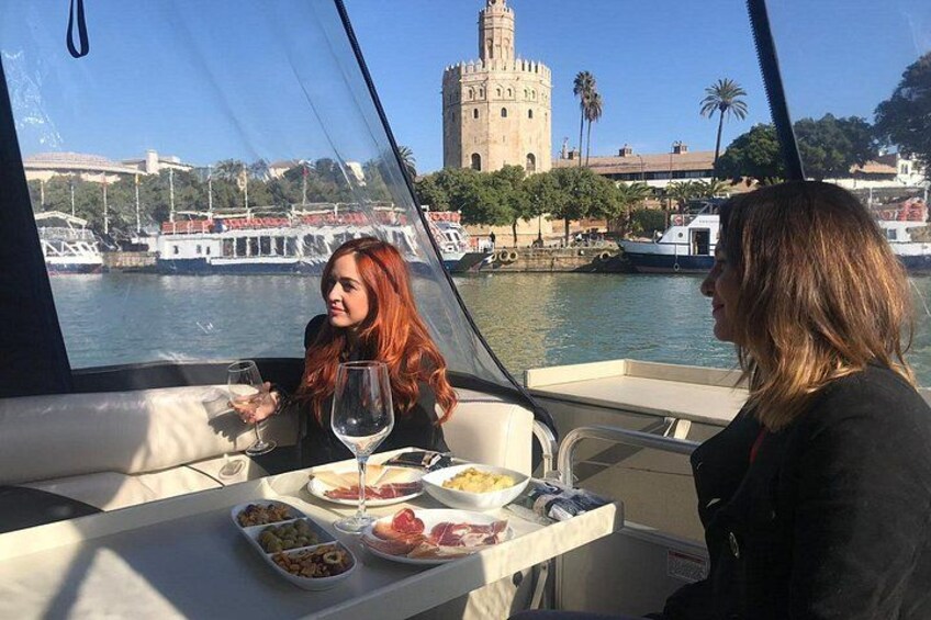 Een boot met twee personen aan het dineren, een waterlichaam en een historische toren op de achtergrond. 2