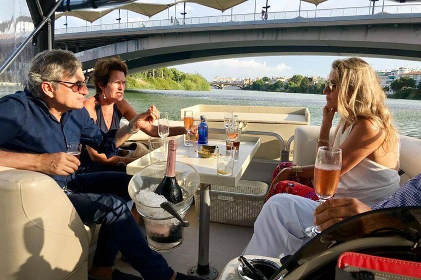 Een groep mensen op een boot, met een fles champagne en een glas wijn op tafel. 4