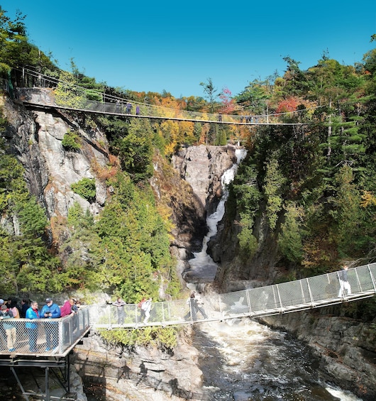 A suspension bridge over a waterfall, surrounded by autumn foliage. 5
