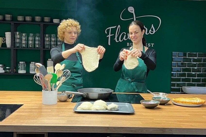 Two people preparing food in a kitchen with a green wall and a sign that reads 'Flavors Best.' 3