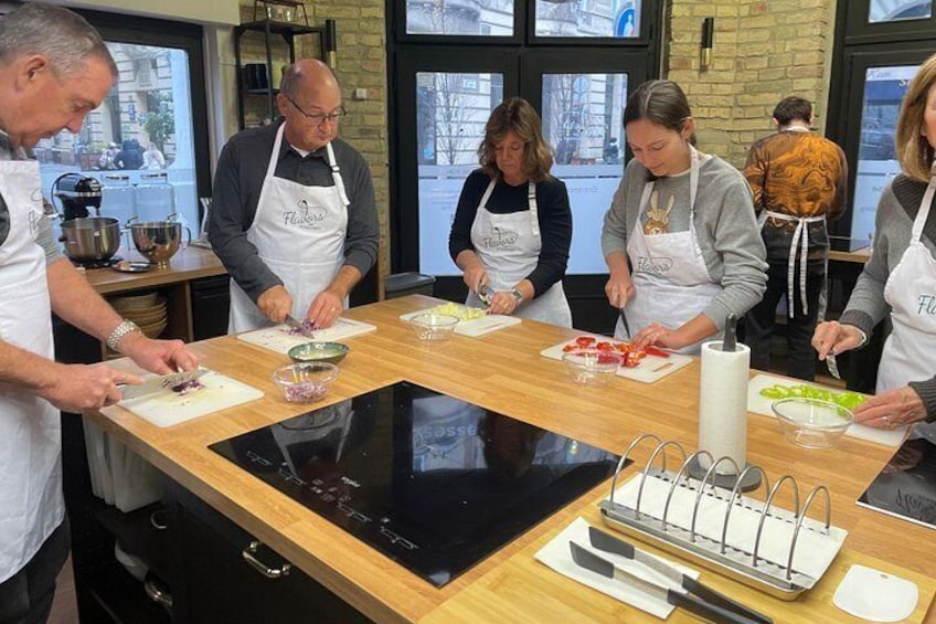 A group of people in aprons preparing food on a wooden table with a black induction cooktop. 2