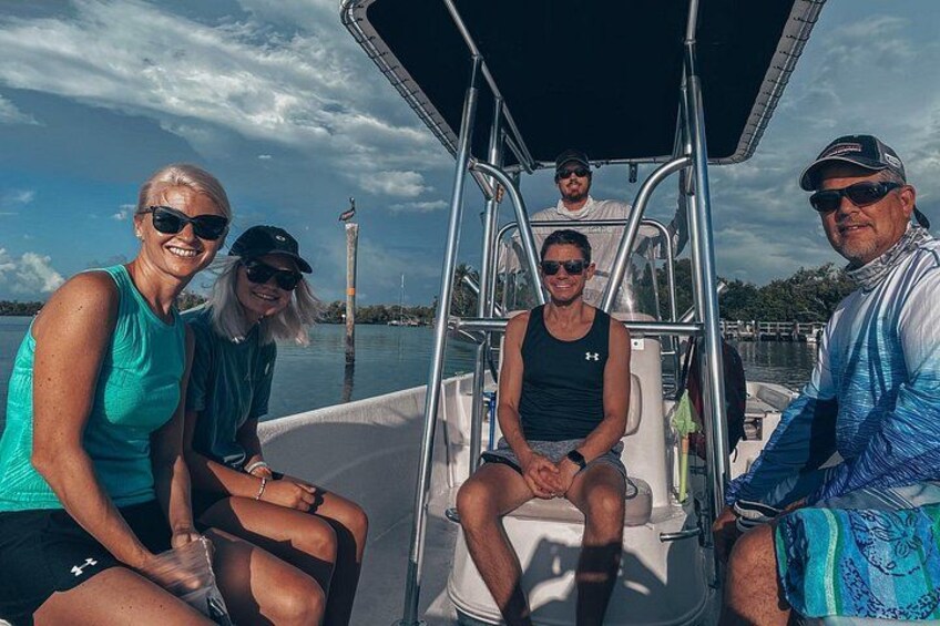 Un groupe de personnes se trouve sur un bateau, avec une étendue d’eau et un quai en arrière-plan. 5