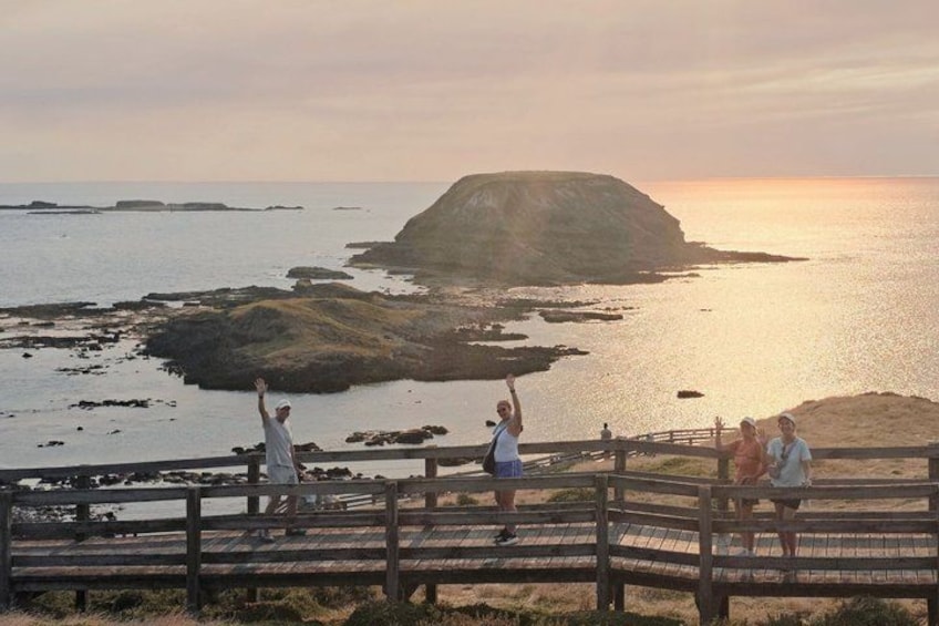 A coastal landscape with a wooden boardwalk, rocky formations, and a sunset. 3