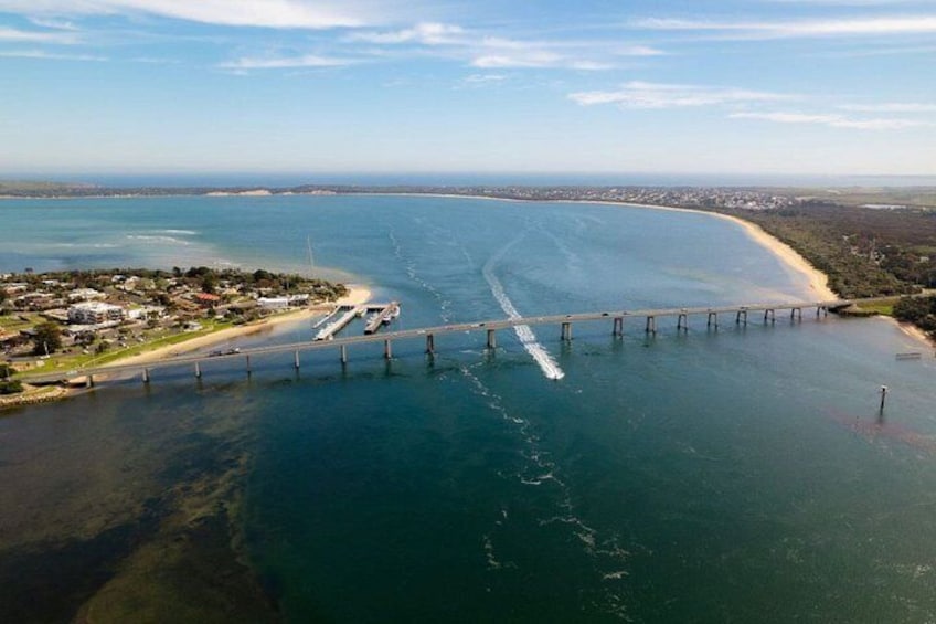 Eine Luftaufnahme einer Küstenlandschaft mit einer Brücke, einem Strand und einer Halbinsel mit Gebäuden. 4