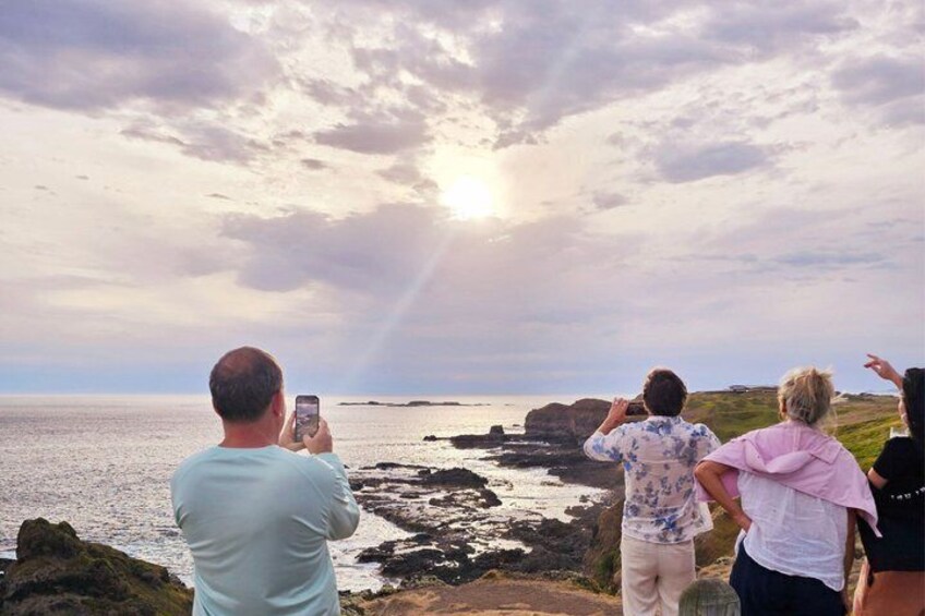 Un gruppo di persone che fotografano un paesaggio costiero con scogliere e l'oceano. 5