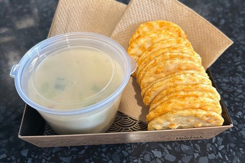 A container of soup and a folded pastry on a textured surface. 3