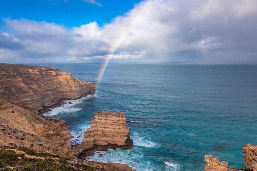 A coastal landscape with cliffs, ocean, and a rainbow. 5