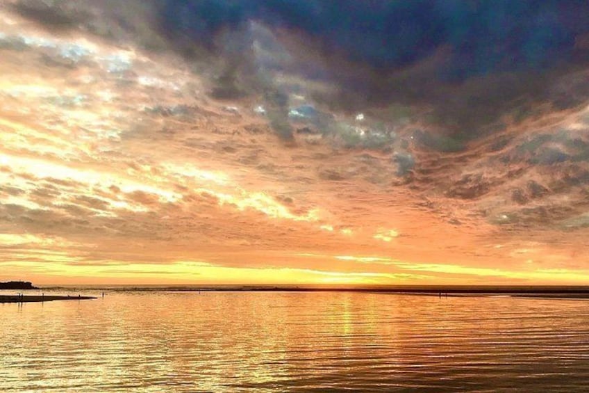A sunset over a calm body of water with a pier extending into the water. 4
