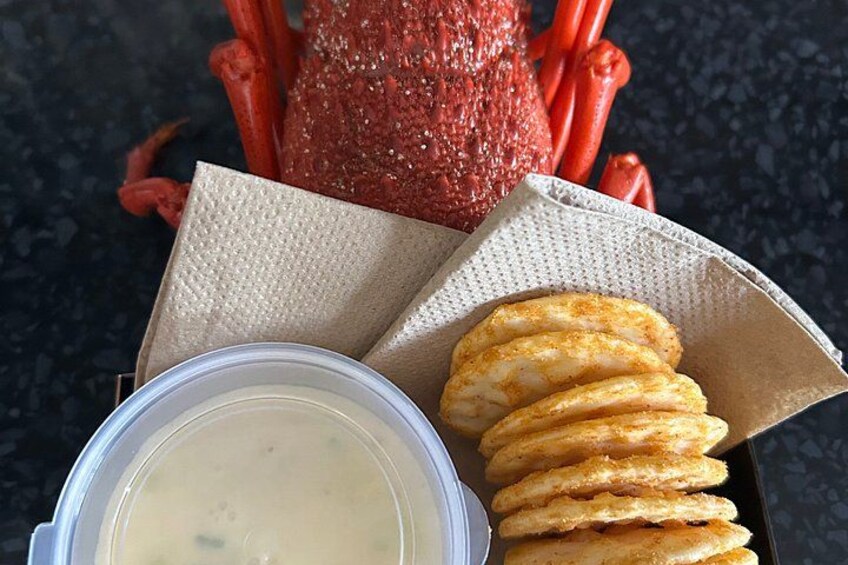 A container with a food item, a paper napkin, and a plastic container with a creamy substance. 2