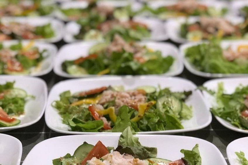 A table with multiple white plates of salads. 5