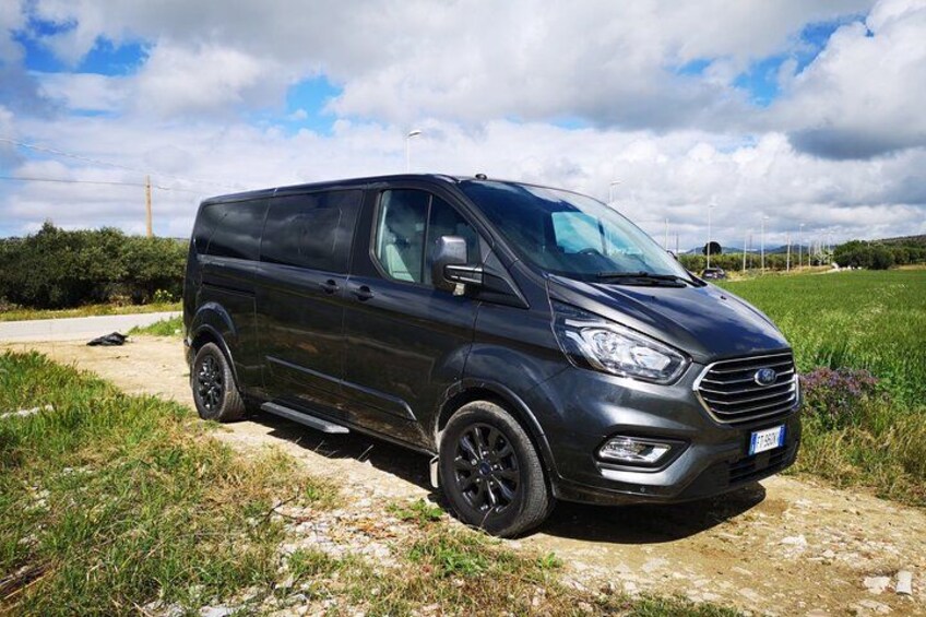 En svart skåpbil stod parkerad på en grusväg, med gräs på båda sidor. 4