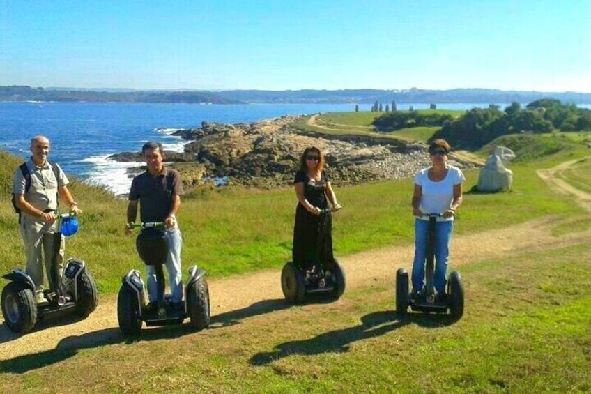 Trois personnes sur des Segways, sur un sentier côtier, avec l’océan et un paysage rocheux en arrière-plan. 5