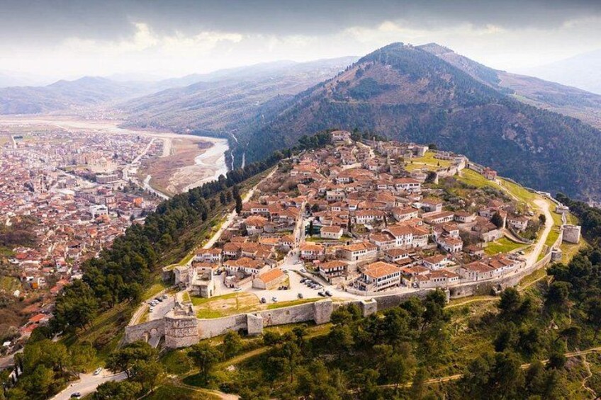 A town with a historic fortification, surrounded by hills and a river. 3