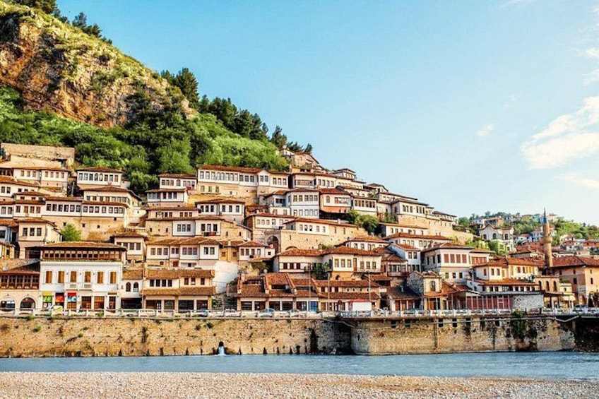 A hillside settlement with terraced houses, a bridge, and a river. 1