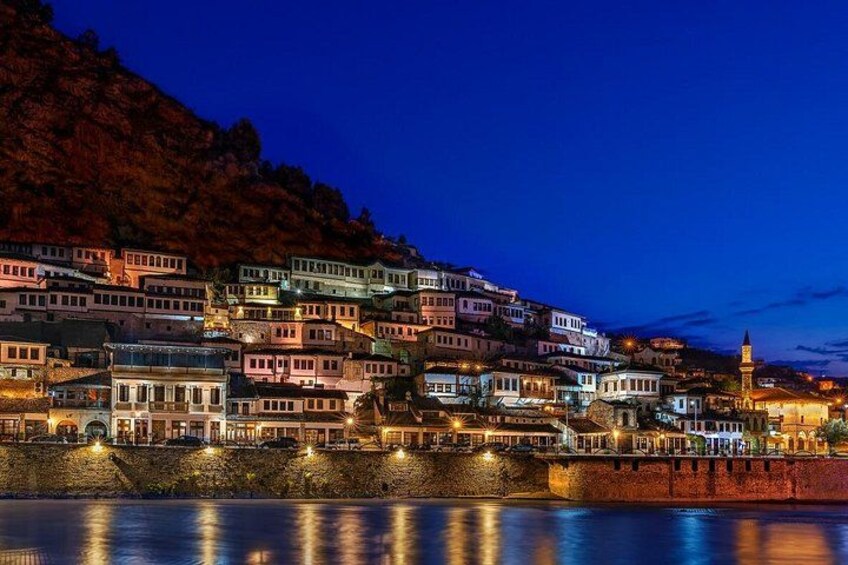 A coastal town at night with illuminated buildings and a prominent tower. 5