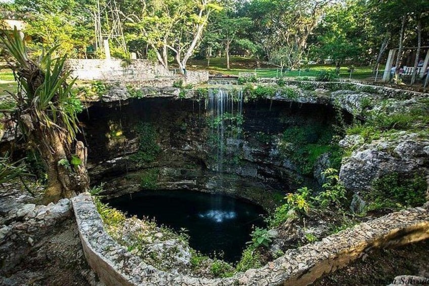Een natuurzwembad met een waterval, omringd door groen en rotsen. 3