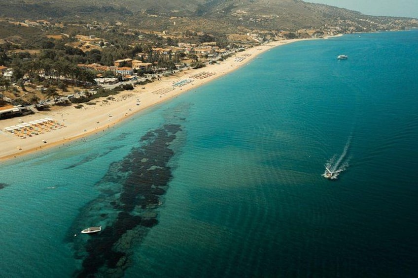 An aerial view of a coastal area with a beach, boats, and a clear waterway. 3