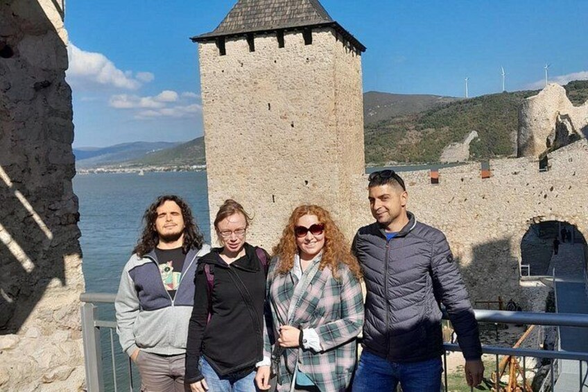 Un grupo de personas de pie frente a una torre de piedra junto al agua. 3