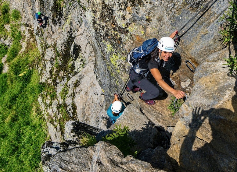 A person rappelling down a rocky cliff with a harness and helmet. 1