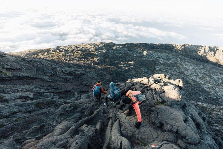 Hikers on a rocky mountain path with a cloudy sky in the background. 2