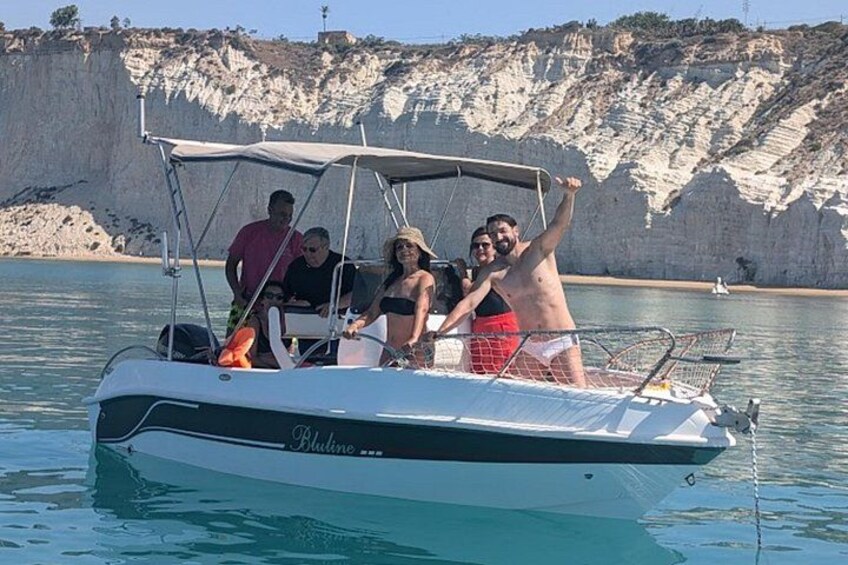 Un bote con gente, agua y acantilados al fondo. 2