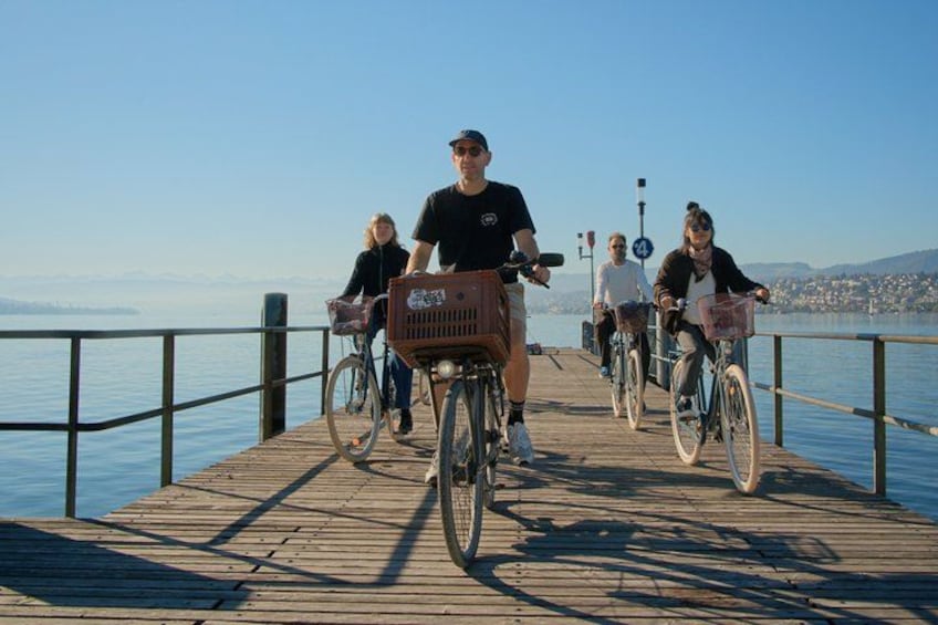 En træbro strækker sig ud i vandet, hvor cyklister cykler. 3