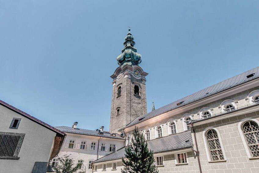 Et historisk tårn med et ur, omgivet af bygninger i klassisk arkitektur. 4