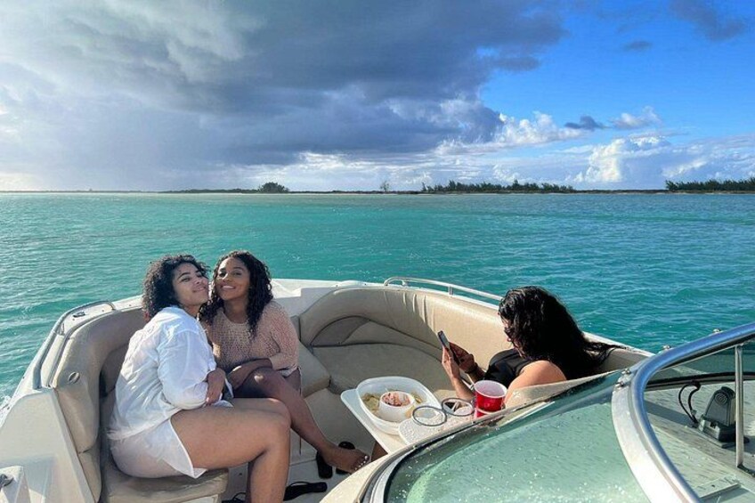 Three people on a boat with turquoise water and a cloudy sky. 1