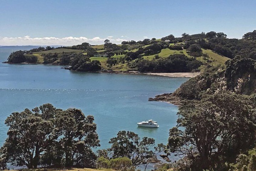 Un paysage côtier avec un bateau sur l’eau, des collines et des arbres. 1