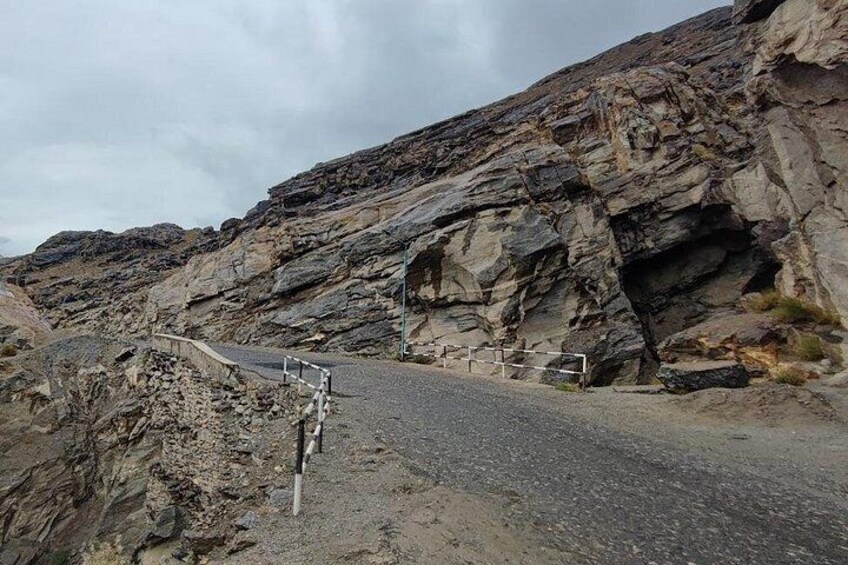 A rocky road with a guardrail and a stone wall. 5