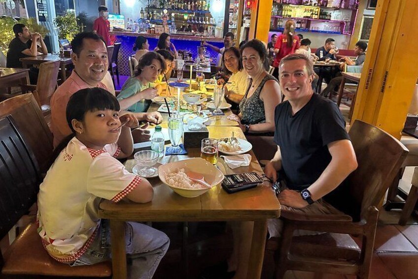 Un grupo de personas cenando en un restaurante con mesas y sillas de madera. 1