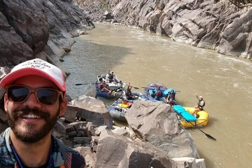 A group of people rafting on a river surrounded by rocky terrain. 1