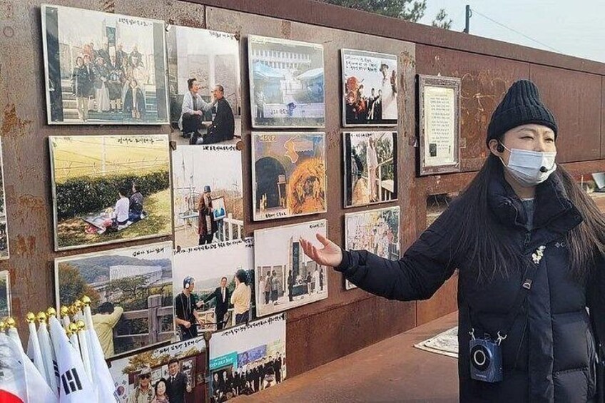 A person standing in front of a wall with multiple framed pictures. 5
