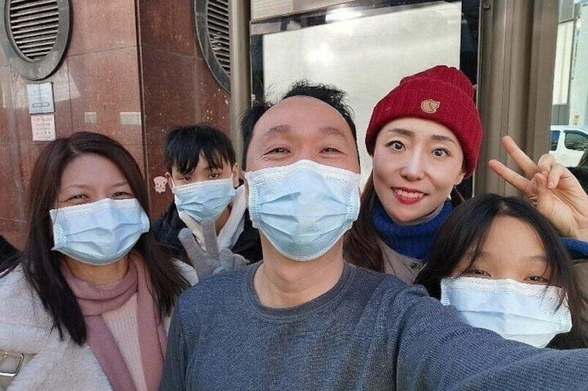 A group of people taking a selfie in front of a building with circular windows and a door. 4