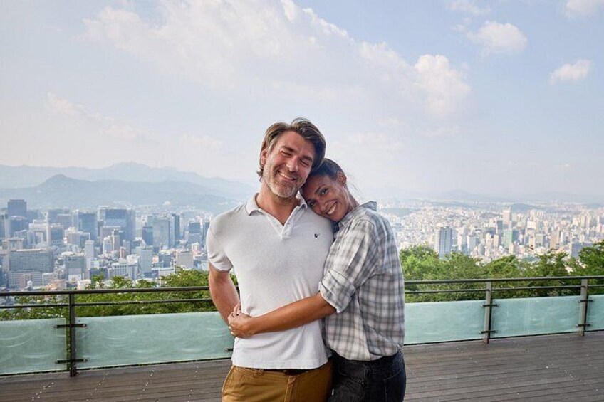 Dos personas abrazándose en una azotea, con un paisaje urbano al fondo. 1