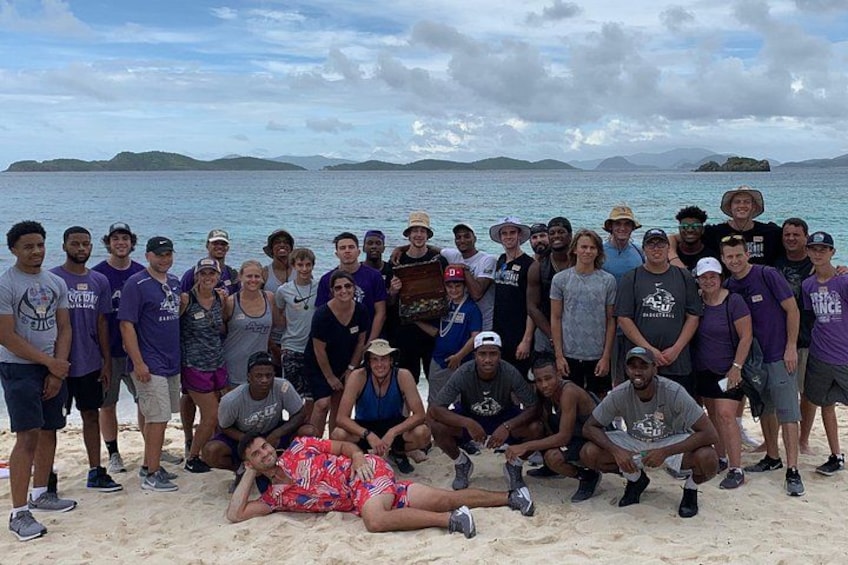 A group of people on a beach with a body of water and islands in the background. 3
