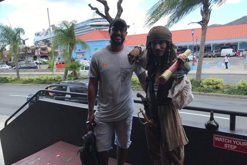 A person in a pirate costume standing next to a vehicle with a sign that reads 'WATCH YOUR STEP'. 2